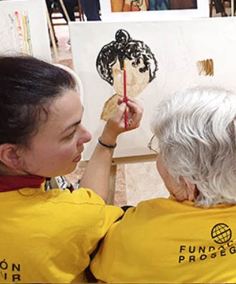 Voluntaria ayudando a pintar un cuadro a una anciana Voluntaria ayudando a pintar un cuadro a una anciana