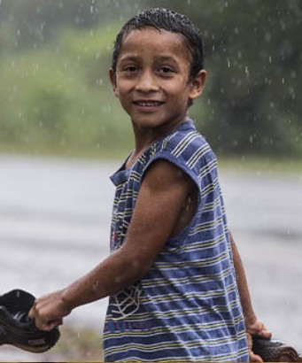 Niño caminando baja la lluvia Niño caminando baja la lluvia